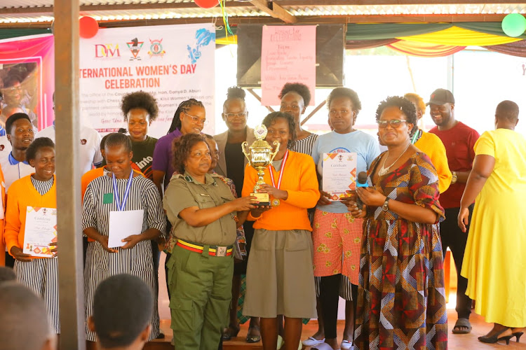 Kisii's Women Prison officer in charge Margaret Waithera awards the overall trophy to Peris Ondara.