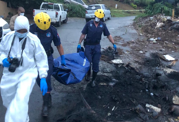 Police and forensic officials remove the bodies of the men accused of murdering alleged drug dealer Teddy Mafia. The men were shot, decapitated and then set alight after the hit.