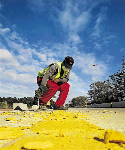 SMALL GLITCH: A worker smashes off some of the 8km of Netherlands-made thermoplastic road barrier and rumble strips on the edge of the Gonubie Main Road Picture: MIKE LOEWE