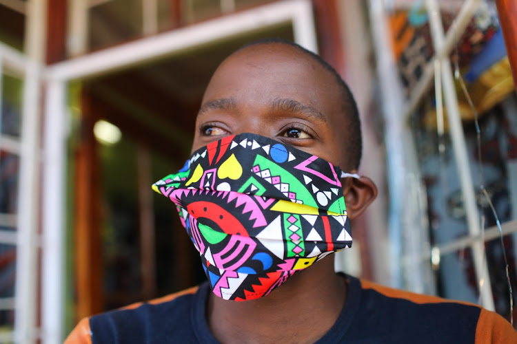 Nhlanhla Nkosi poses for a picture with his fashionable mask, on March 25 2020, at Nkosibo Laundromat and Dry Cleaners in Melville, Johannesburg. The idea to make fashionable masks came when owner Suzan Mazibuko couldn’t find the surgical masks in shops, most being sold out. She got to work and started production using brightly coloured fabrics, cartoon characters and Ndebele patterns which she sells for R30. They are not surgical quality but can be used to accessorise the hospital grade mask. Her small business will be closed over the 21-day lockdown.
