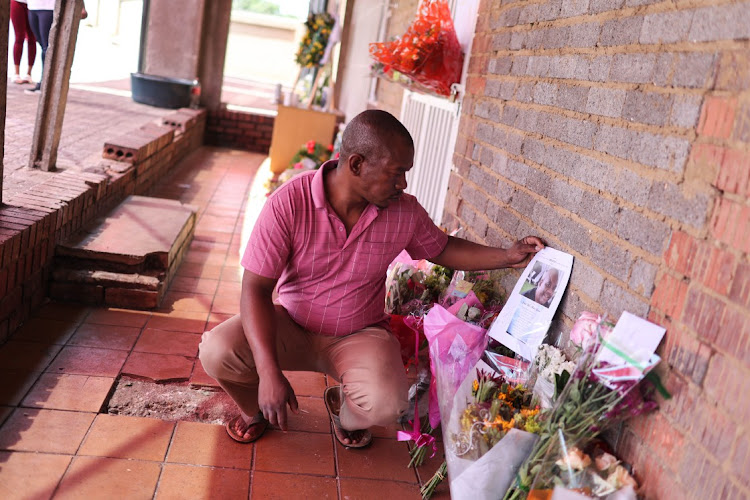 Mpho Sebotsa looks at flowers and messages outside the practice.