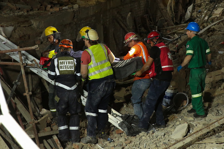 Rescue workers search through the rubble of the collapsed building in Victoria Street, George, on Tuesday