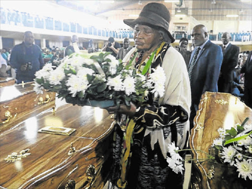 SOMBRE TIME: A handover ceremony in Port Elizabeth of the exhumed remains of 12 UDF activists hanged in 1986. Tyityi Menze lays a wreath on the coffin of her grandchild Makhezwene Menze Picture: FREDLIN ADRIAAN