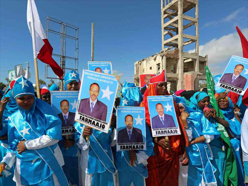 Women carry posters of the newly elected Somalian President Mohamed Abdullahi as they celebrate his victory, near the Daljirka Dahson monument in Mogadishu, Somalia February 11, 2017. /REUTERS