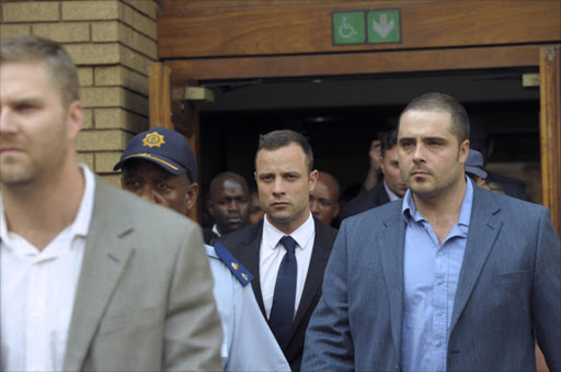 South African amputee Olympian sprinter Oscar Pistorius (C) leaves the Pretoria's North Gauteng High Court on March 6, 2014, on the 4 th day of his trial. Pistorius, 27, is answering charges that he wilfully shot his gilfriend Reeva Steenkamp dead on Valentine's Day 2013 through a locked bathroom door at his home in the city. Oscar Pistorius fired a gun in a restaurant, grazing a friend's foot, and then asked someone else to take the blame, the court heard on March 5 on the third day of the paralympian star's murder trial. AFP PHOTO / ALEXANDER JOE