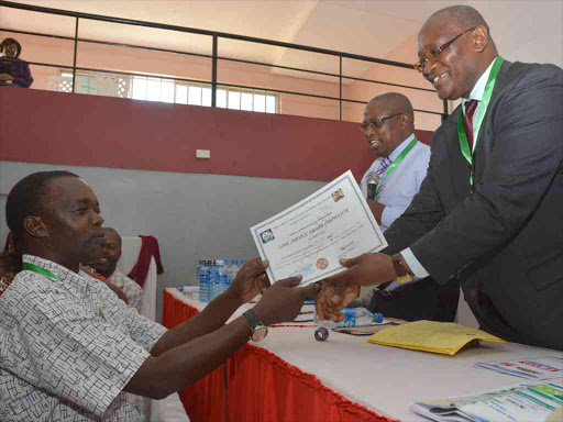 Cardinal Otunga High School, Mosocho principal Zachary Nyariki receives a recognition certificate from Kisii Governor James Ongwae during the Kenya Secondary Schools Heads Association, Kisii branch AGM in Kisumu. Nyariki has served as principal for 32 years. Photo; Angwenyi Gichana