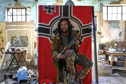 Artist Ayanda Mabulu strikes a carefully arranged pose in front of the war flag of the Third Reich at Victoria Yards studio in Lorentzville, Johannesburg.