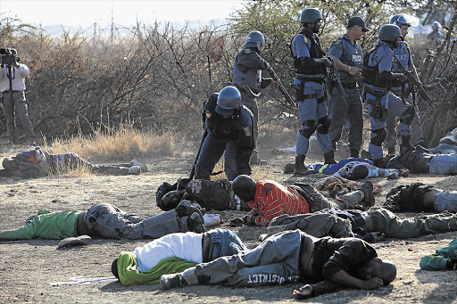 Police stand over dead and injured miners in Marikana, near Rustenburg, on August 16. The commission of inquiry into the shooting saw video footage and listened to voice recordings that captured the last moments before police opened fire.
