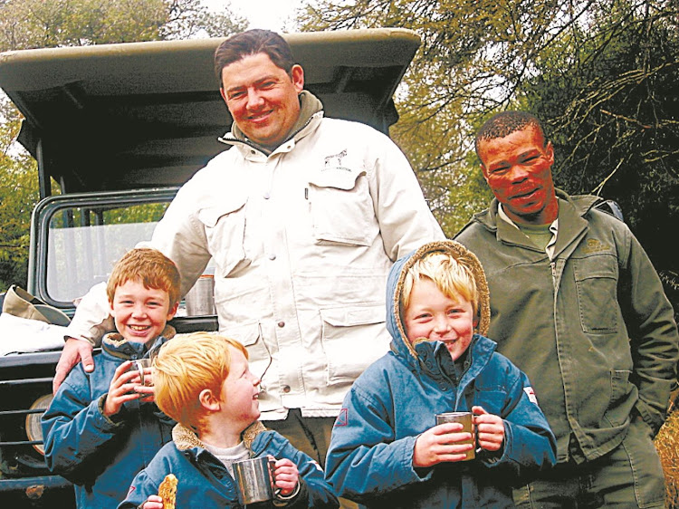 The Rogers boys, front from left, Ben, 8, Jude, 4, and Nic, 6, enjoy a mug of hot chocolate with guides Dave McNaughton, left, and Alroy Pietersen during a drive in Samara Game Reserve, near Graaff-Reinet, in 2009