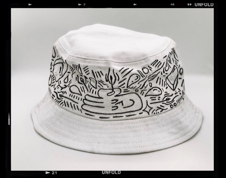 Abrahams's unique bucket hat design features his signature ‘A-Okay’ hand holding a lit match stick