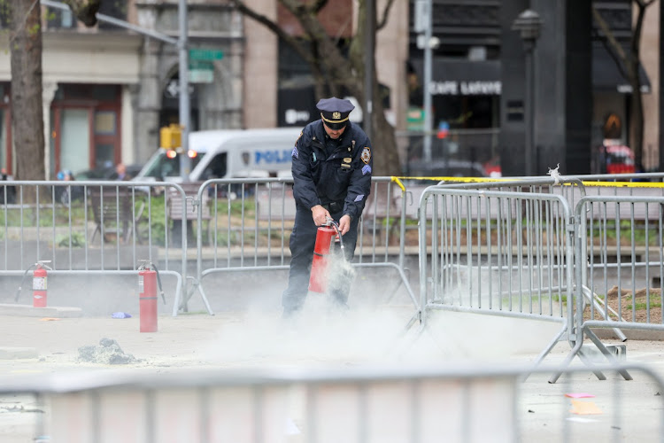 A police officer uses a fire extinguisher as emergency personnel respond to a report of a person covered in flames, outside the courthouse where former U.S. President Donald Trump's criminal hush money trial is under way, in New York, U.S., April 19, 2024.