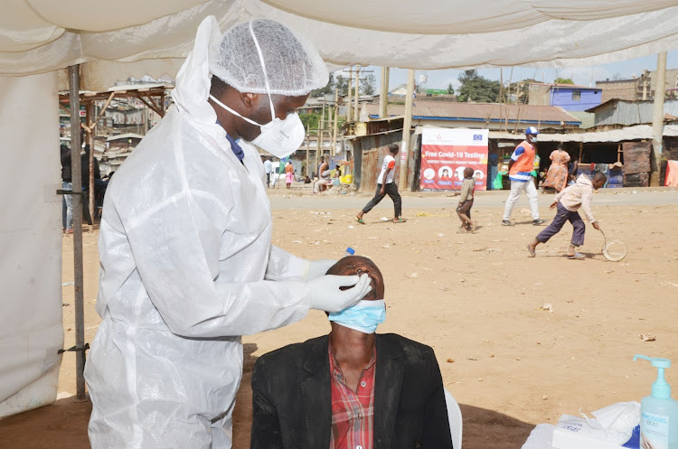 Kennedy Wafula, a laboratory technologist at Aga Khan University Hospital, obtains a swab sample from a Mathare resident during a free Covid-19 PCR testing on August 17,