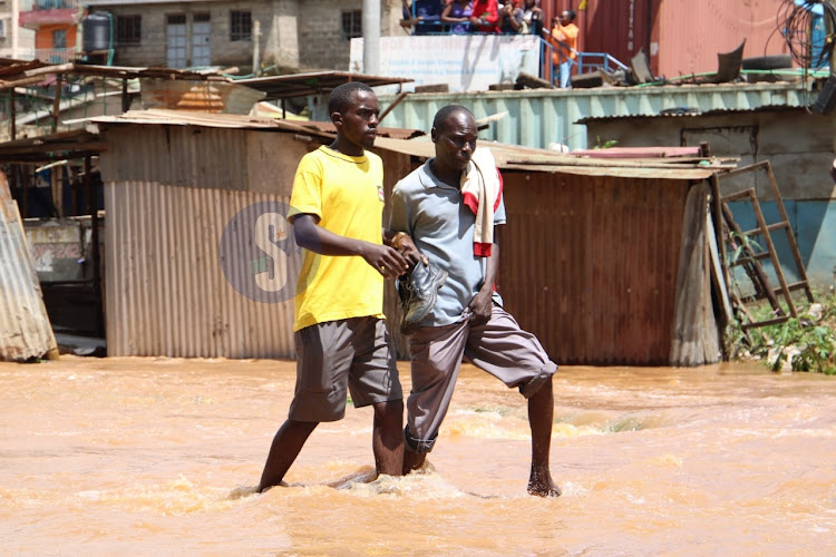 Pedestrians cross a flooded road in Kasarani on April 24, 2024.