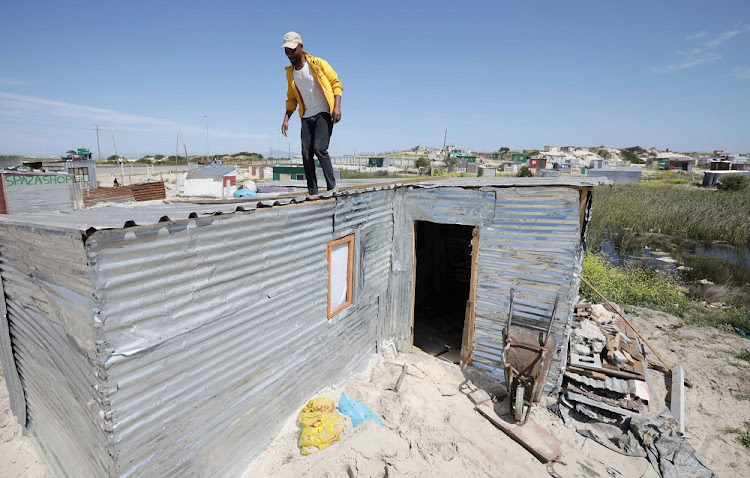 Zenithulu Yukuthwane walks on the roof of the shack he built after a group of people invaded land in the Driftsands Nature Reserve in Cape Town. File image