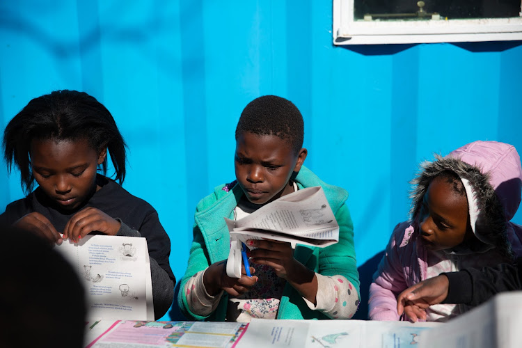 Children cut out a Nal’ibali booklet at the Ikageng Library in Orlando West, Soweto.