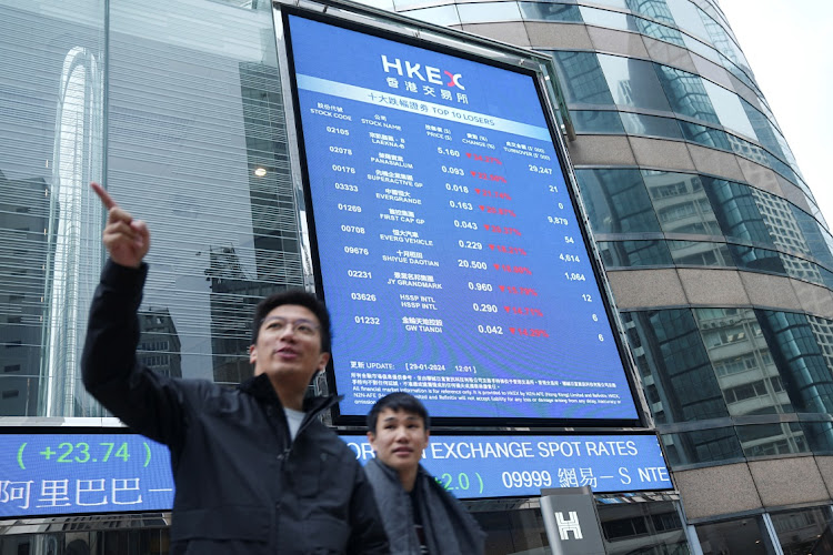 People walk in front of a screen displaying Evergrande's stock prices among others outside the Exchange Square in Hong Kong, China. Picture: REUTERS/LAM YIK