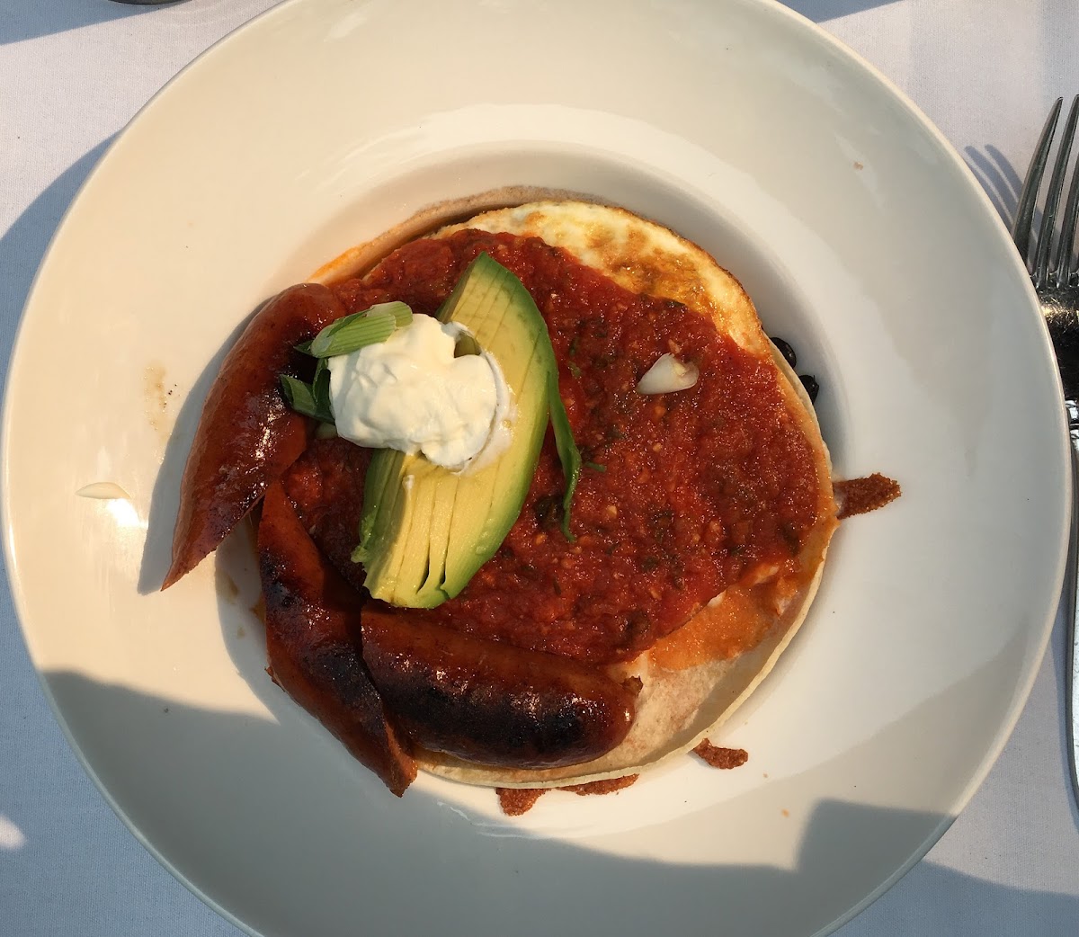 Huevos Rancheros with Andouille Sausage. Sour cream, avocado and salsa over eggs, tortillas and black beans.