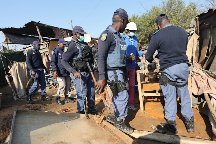Members of the police holding bolt cutters used to dismantle equipment used by illegal mining operations make their way onto the scene, 06 July 2023, at Angelo Informal Settlement in Boksburg, Ekurhuleni.