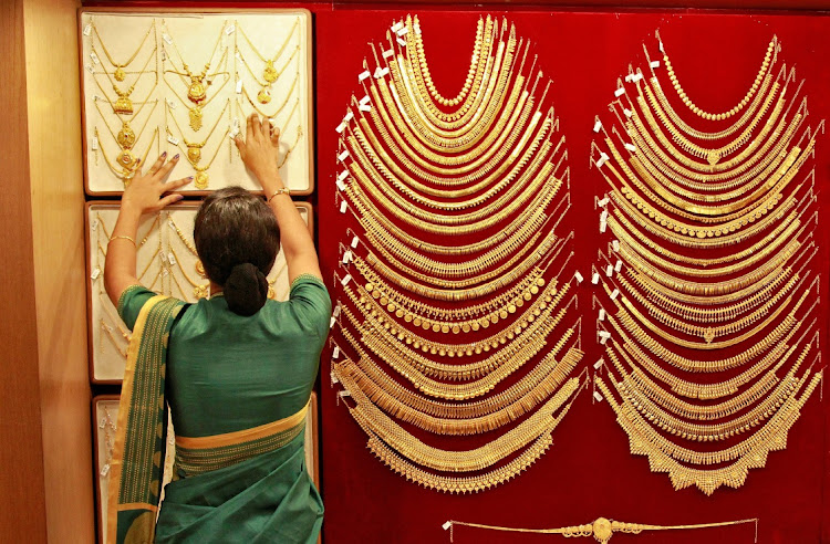 A saleswoman arranges a gold necklace inside a jewellery showroom in the southern Indian city of Kochi. Picture: REUTERS/SIVARAM V