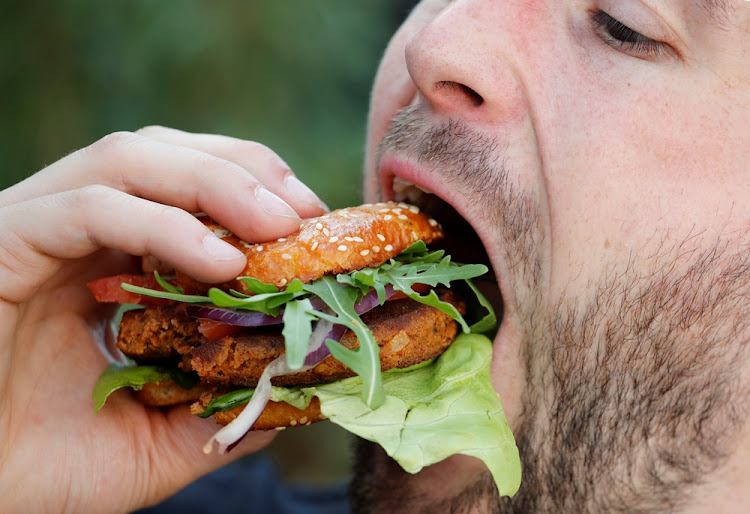 Max Kraemer of the start-up "Bug Foundation" bites into a hamburger made of Buffalo worms (Alphitobius Diaperinus) during its premiere in a supermarket in Aachen, Germany, on April 20, 2018.