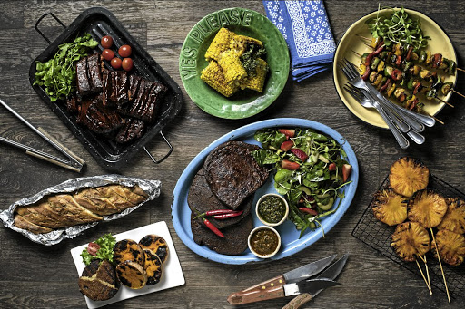 Seitan ribs and steaks pictured with an assortment of braaied veggie sides.