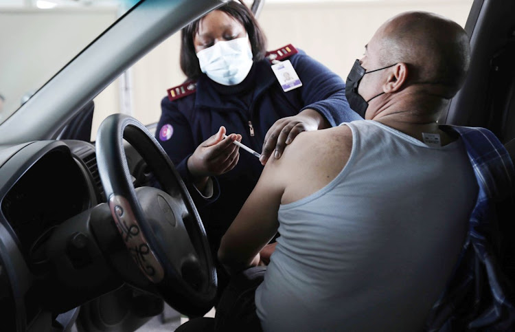 A healthworker at the Athlone Stadium drive-through vaccination site in Cape Town gives a motorist his Covid-19 jab.