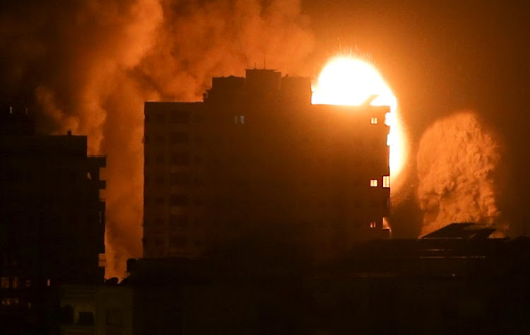 Smoke and flames rise above a building during Israeli air strikes amid a flare-up of Israeli-Palestinian violence in Gaza City on May 17, 2021.