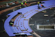 Workers install the Paris 2024 Olympic and Paralympic Games' athletics track of two shades of purple manufactured by Mondo Sports Flooring inside the Stade de France, in Saint-Denis near Paris on April 9. 