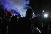 Smoke from police munition rises in the background near protesters rallying outside the Brooklyn Center Police Department, days after Daunte Wright was shot and killed by a police officer, days after Daunte Wright was shot and killed by a police officer, in Brooklyn Center, Minnesota on April 13, 2021. 