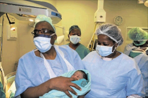 BUNDLE OF JOY: Minister Aaron Motsoaledi holds baby Refilwe Aronica Mashitisa whom he helped to deliver at Mankweng Hospital in Limpopo. PHOTO: ELIJAR MUSHIANA