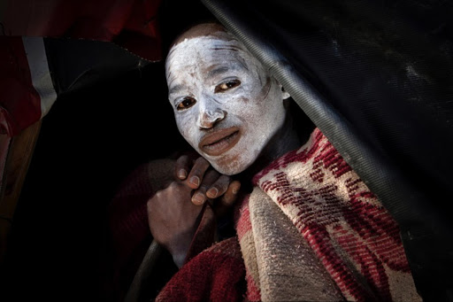 A young Xhosa initiate sits at the entrance of a tarpaulin shelter at Sunday’s River Valley, Eastern Cape.