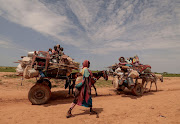 A Sudanese woman who fled the conflict in Murnei in Sudan's Darfur region walks beside carts carrying her family belongings upon crossing the border between Sudan and Chad in Adre, Chad, on August 2 2023. File image: Reuters/Zohra Bensemra