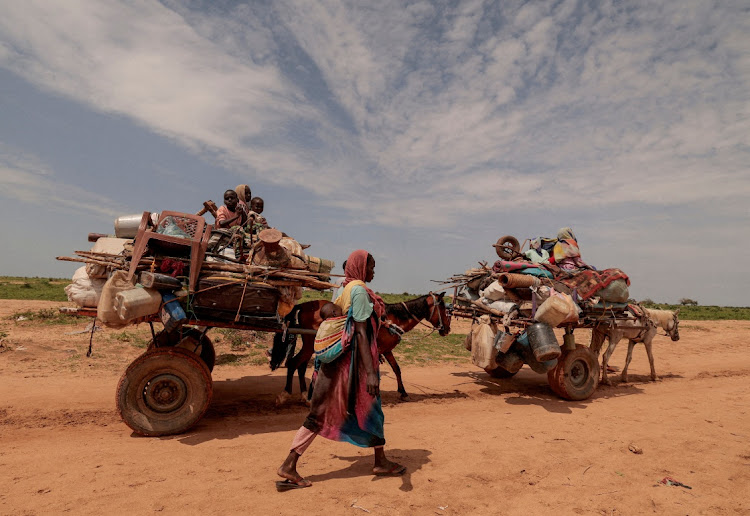 A Sudanese woman who fled the conflict in Murnei in Sudan's Darfur region walks beside carts carrying her family belongings upon crossing the border between Sudan and Chad in Adre, Chad, on August 2 2023. File image: Reuters/Zohra Bensemra