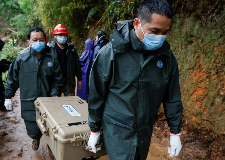 Workers carry a case at the site where a China Eastern Airlines Boeing 737-800 plane flying from Kunming to Guangzhou crashed, in Wuzhou, China on March 24, 2022. The magnitude and horror of the crash defies aviation logic, the writer says.