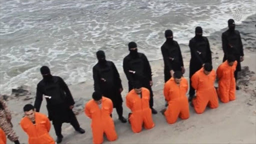 Men in orange jumpsuits purported to be Egyptian Christians held captive by the Islamic State (IS) kneel in front of armed men along a beach said to be near Tripoli. REUTERS/Social media via Reuters TV
