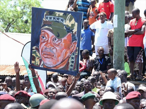 Nyalenda residents wave a portrait of President Uhuru Kenyatta when he toured the slum and launched a youth empowerment and slum upgrading project, April 2015. /PSCU