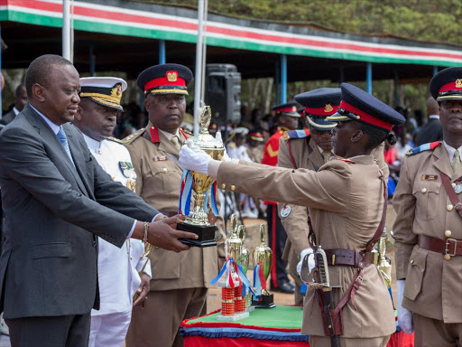 President Uhuru Kenyatta presents a trophy to the third-best all-round recruit Asha Naaman, Kenya Army, during the recruits’ passing-out parade at the Recruits Training School, Eldoret, Uasin Gishu county, yesterday /PSCU