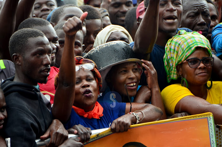 An Azimio supporter among others use a sufuria to cover her head as rain drops during a mass action rally led by Azimio leader Raila Odinga in Nakuru on March 16, 2023.