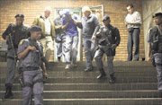 CHAINED: Zimbabwean national Bongani Moyo, face covered, arrives in the Pretoria magistrate's court in leg irons to face, among others, charges of armed robbery.  Photo: PEGGY NKOMO