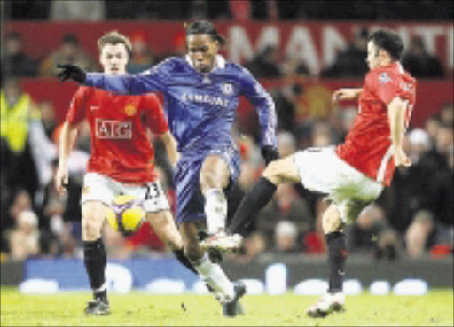 SANDWICHED: Chelsea's Didier Drogba, center, and Manchester United's Ryan Giggs, right, battle for the ball during the English Premier League soccer match at Old Trafford, Manchester, yesterday. 11/01/2009. Pic. Martin Rickett. © AP
