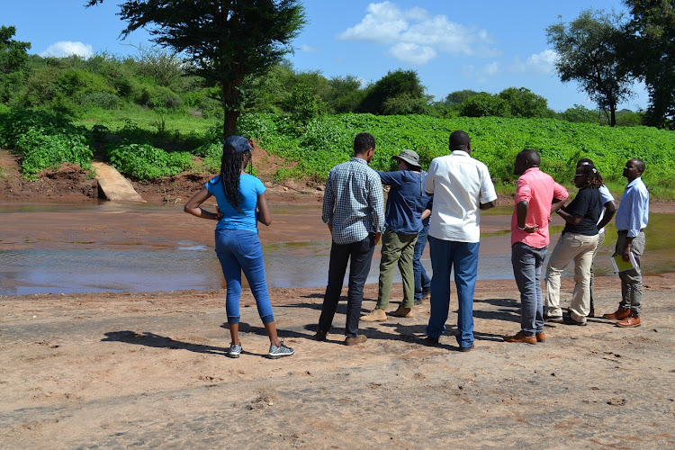 The delegation at the Mwitasyano River Sand dam location on Tuesday. Most of the sand dam wall has been submerged in sand but a section can be seen in the goregraound.