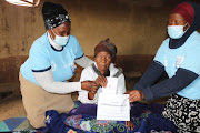 Nomamelika Emily Philiso, 119, of Mandleni villlage casts her vote at her home. She is assisted by IEC presiding officer Phumza Qangani and her deputy Busisiwe Tshalana. 