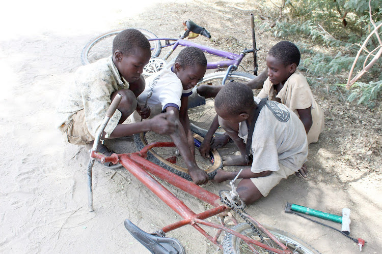 Boys out of school due to the Covid-19 pandemic sit on the street to repair their bicycles after riding in Lodwar, Turkana county