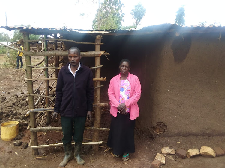 Dan Sugu Ali and his wife Emily Kisa stand next to the house which their son was repairing before being struck by lightning.