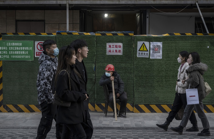 A worker wears a protective mask as he guards a gate at a construction site in a shopping area on November 24 2021 in Beijing, China. Picture: GETTY IMAGES/KEVIN FRAYER