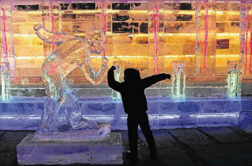 BEIJING, CHINA - JANUARY 19: A young Chinese children plays alongside an ice sculpture at Yanqing Ice Festival January 19, 2016 in Beijing, China on Tuesday. Chinese cities Beijing and Zhangjiakou won the bid to are is one of the host cities for the 2022 Winter Olympic Games on July 31, 2015 in Kuala Lumpur