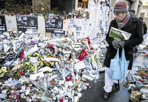 VIVE LE CHARLIE HEBDO: A man with the latest edition of Charlie Hebdo at the improvised memorial on Rue Nicolas Appert, near the satirical magazine's offices in Paris, where many of its staff were killed by two gunmen