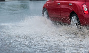 Generic image of a car driving through puddle of water.