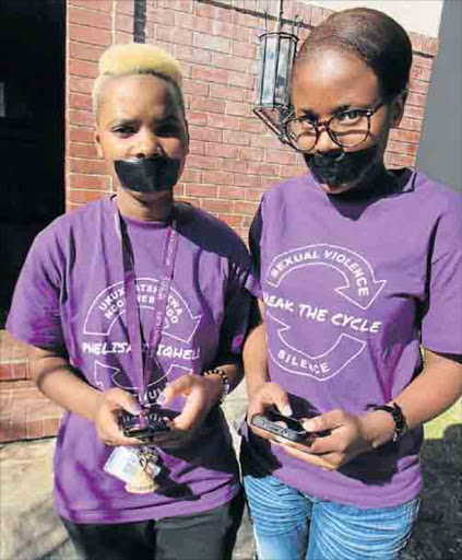 Rhodes University students Abongile James, left, and Athenkosi Nzanzeka, who joined hundreds of others yesterday and taped their mouths shut to protest gender and sexual violence in South Africa, talk to each other using social media