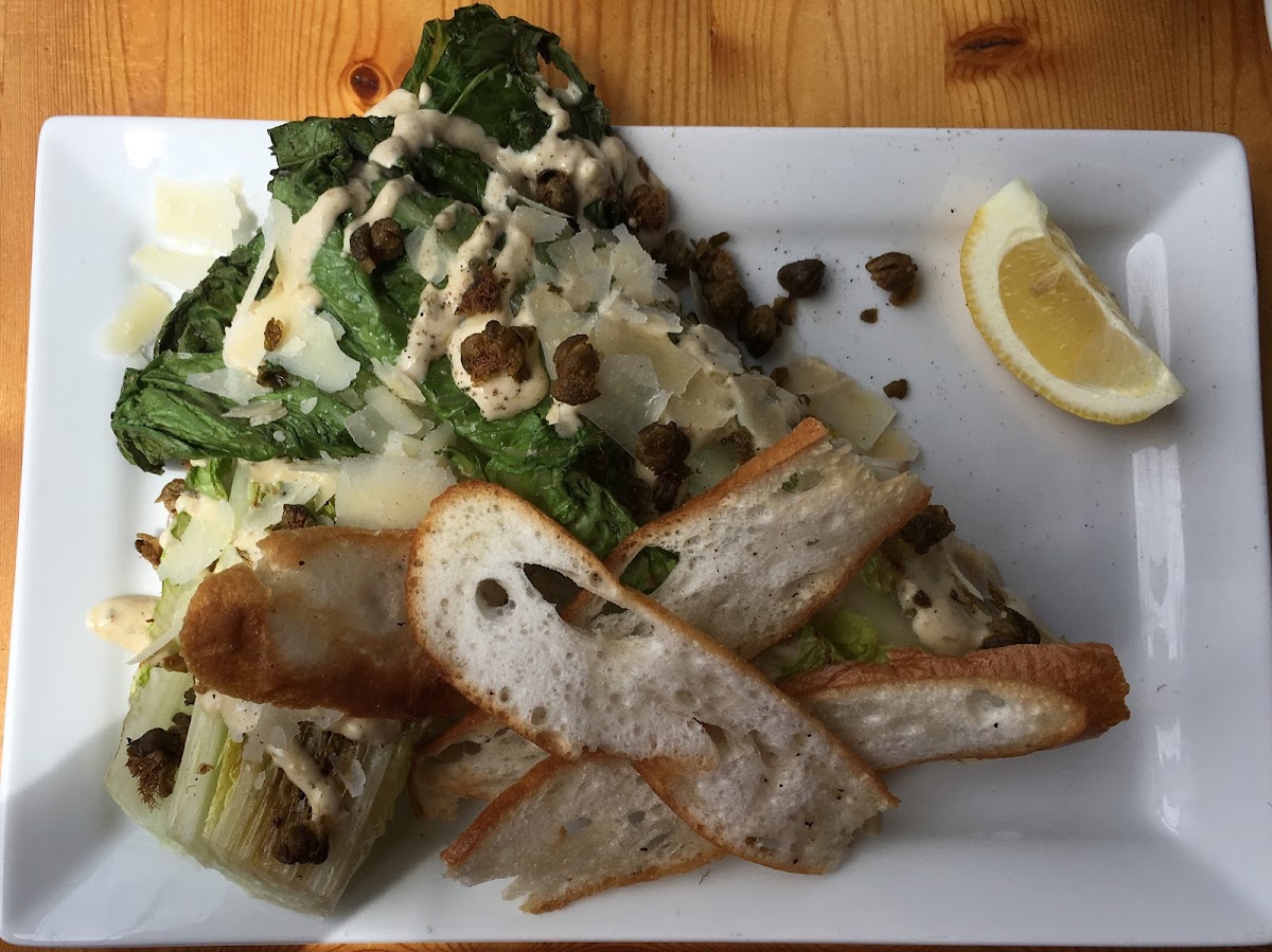 Grilled Caesar: grilled romaine hearts, classic dressing, capers, grana padano (cheese) with gluten free crostinis.